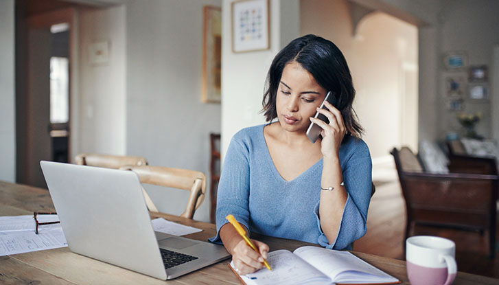 Sales professional managing follow-up calls and notes while working on a laptop, representing an effective follow-up sales process.